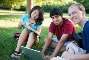 Group of three happy teenagers studying